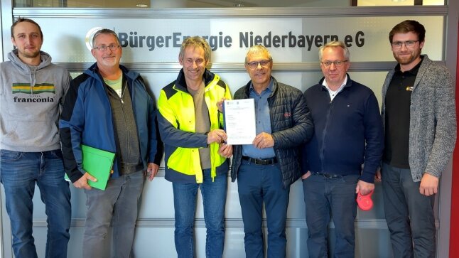 6 Männer stehen vor einer Wand zusammen und halten ein Schreiben mit Unterschriften in die Höhe