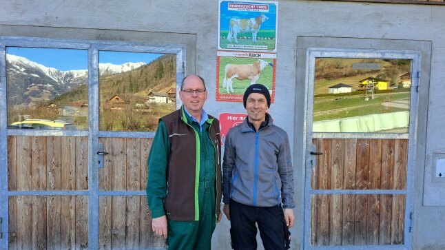 zwei Männer vor einem Tor mit Plaketten