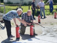 Feurlöschübung. Zwei menschen bedienen den Feuerlöscher