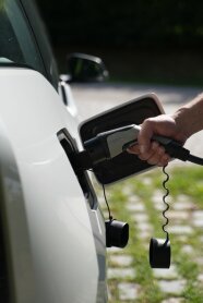 Hand hält Elektroladekabel an E-Auto