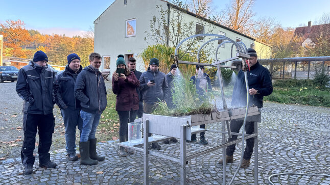 Eine Gruppe Landwirtschaftsschüler schaut sich einen Regenerosions-Versuchsaufbau an