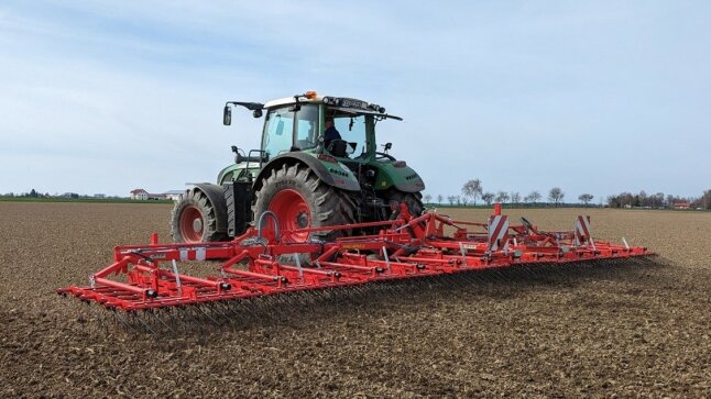 grüner Traktor mit roten Felgen und rotem Unkrautstriegel