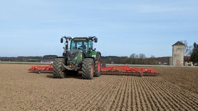 grüner Traktor mit roten Felgen und rotem Unkrautstriegel