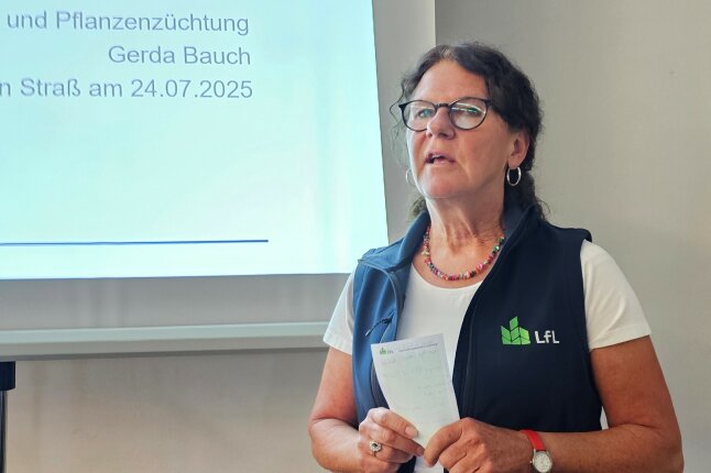 Eine Frau steht mit einem Zettel vor einer Präsentationswand und redet