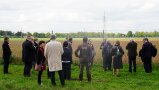 Menschengruppe steht auf einer grünen Wiese vor einer PV Anlage