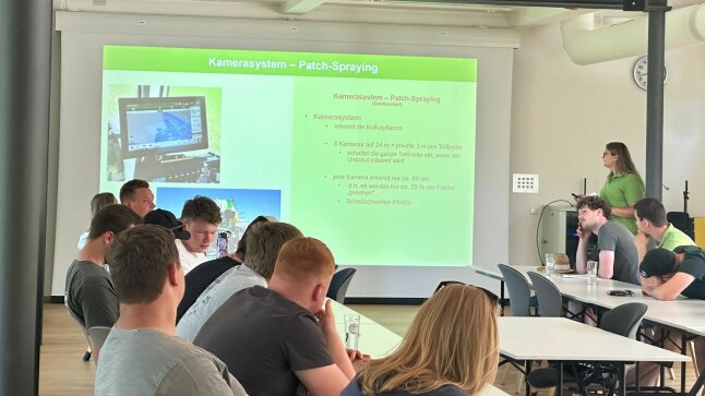 Eine Präsentation läuft über die Beamerwand - davor sitzen Schüler