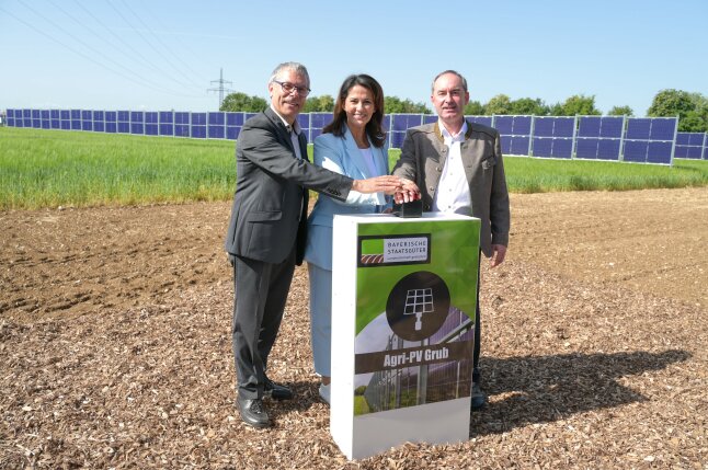 Dippold-Kaniber-Aiwanger stehen vor einer PV Anlage und drücken den Startknopf