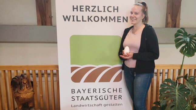 Abschlussprüfling vor BaySG Logo