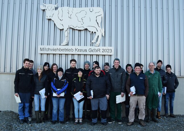 Ein Gruppenbild mehrerer Menschen vor einer Wand des Milchviehbetriebes Kraus GdbR